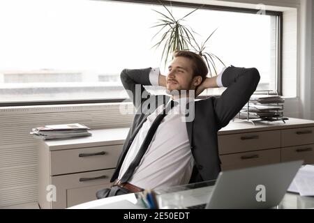 Satisfied businessman stretching in office chair after work done Stock Photo