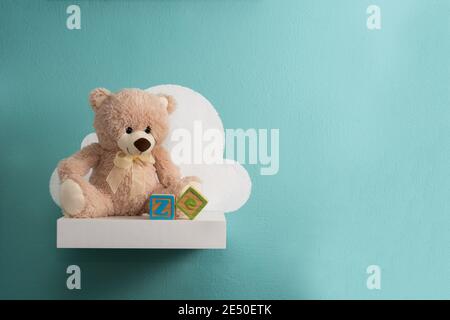 Teddy bear on white shelf and turquoise wall Stock Photo