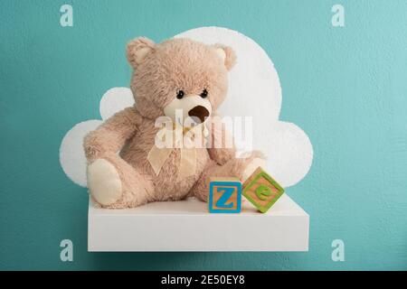 Teddy bear on white shelf and turquoise wall Stock Photo