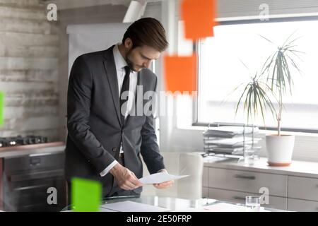 Serious businessman reading documents, checking financial report in modern office Stock Photo