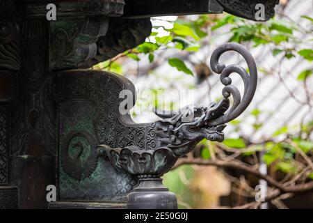 Close up of a decorative bronze sculpture portraying a flaming japanese dragon, against a bokeh background Stock Photo