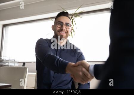 Close up smiling Arabian candidate shaking employer hand, getting job Stock Photo