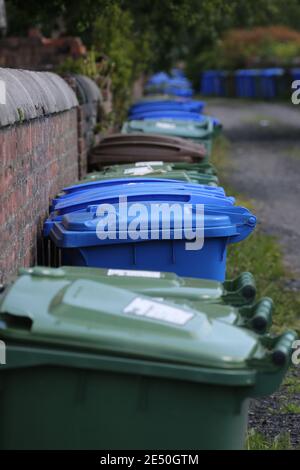 Long line of different coloured wheelie bins in lane at back of house ...