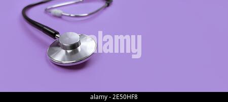 Black stethoscope on a purple background with copy space. Stock Photo