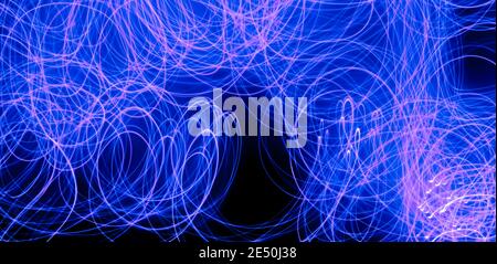 Long exposure blue lights abstract texture background. Blue lights drawing patterns on black background. Stock Photo