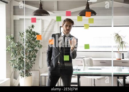 Confident businessman working on project plan, looking at sticky papers Stock Photo