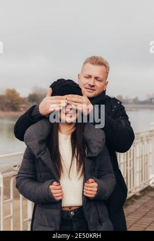 In love with the couple, the man covers the smiling girl's eyes with his hands. High quality photo Stock Photo