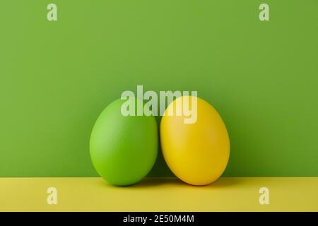 Painted Easter eggs on green and yellow background, spring holiday preparation Stock Photo