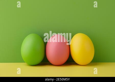 Painted Easter eggs on green and yellow background, spring holiday preparation Stock Photo