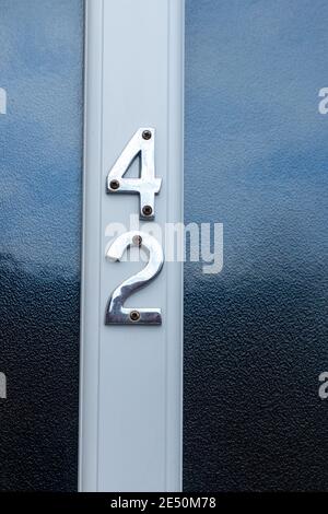 Number 42 in shiny metal digits on a white door with frosted glass