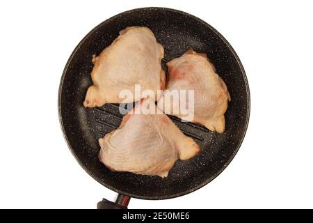 Raw chicken thighs laying in grill pan isolated on white background. Top view Stock Photo