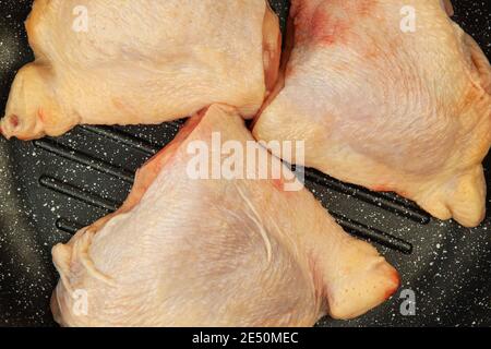 Raw uncooked chicken thighs laying in grill pan. Close up Stock Photo