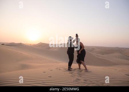 Abu Dhabi, UAE - October 6 2017: Two British female tourists of African descent take a selfie at sunset at the Empty Quarter Desert (Rub' al Khali). Stock Photo
