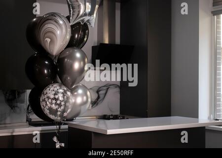 Corner of stylish Minimalistic grey kitchen, dark gray cupboards, white countertops and bar. black and white balloons. High quality photo Stock Photo