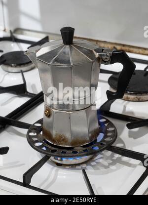 A small Moka coffee pot on a gas hob using a reducer ring trivet