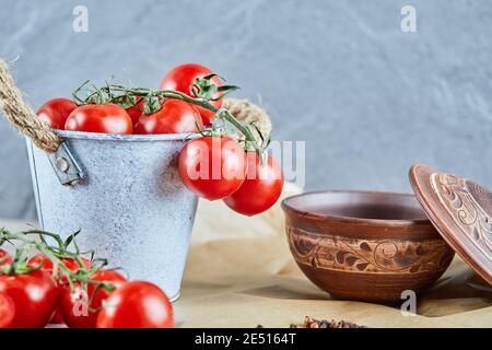 Bucket of tomatoes and empty bowl on blue background Stock Photo