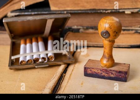 Wooden stamp for stamping and cigarettes in a metal cigarette case. Office accessories in the old office. Dark background. Stock Photo