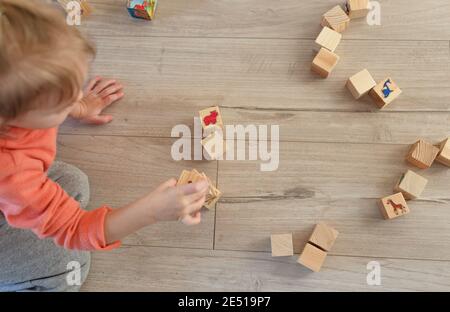 a child plays on the floor with wooden cubes. The view from the top Stock Photo
