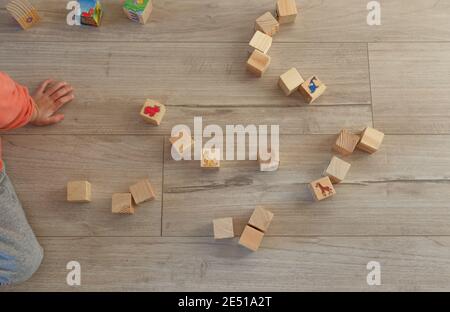 a child plays on the floor with wooden cubes. The view from the top Stock Photo