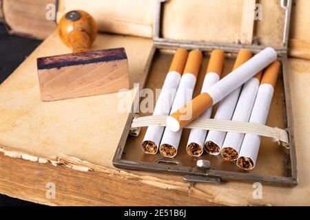 Wooden stamp for stamping and cigarettes in a metal cigarette case. Office accessories in the old office. Dark background. Stock Photo