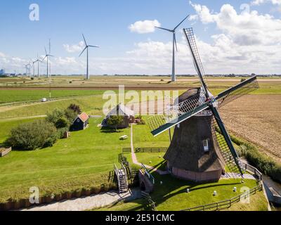 Aerial wide angle view of an ancient windmill against large wind farm of modern wind turbines Stock Photo