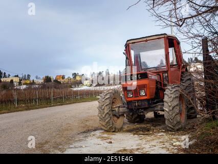 Old tractor with a snowy mountain village in the background, Spiazzi in the province of Verona Stock Photo
