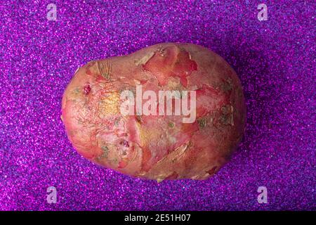 Red Potato on Glittering Purple Background. Aerial Macro Shot. Stock Photo