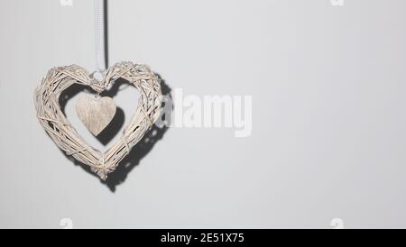 Braided heart hanging on the background wall, concept theme Love, 14 february Stock Photo