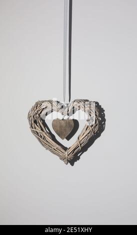 Braided heart hanging on the background wall, concept theme Love, 14 february Stock Photo