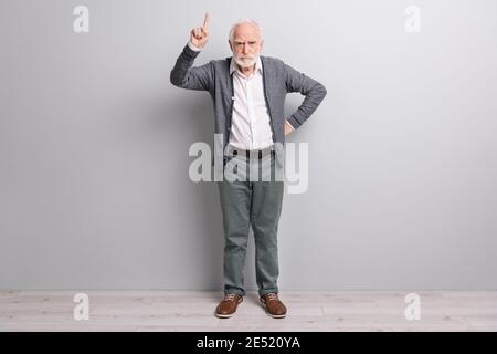 Full size photo of old sad man finger up wear dark sweater trousers boots isolated on grey wall Stock Photo