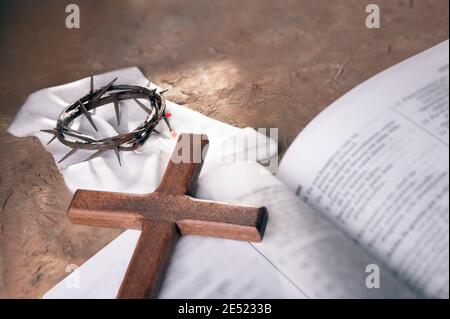 Crown of thorns and Wooden cross over open bible background with copy space for inscription. Christian Easter concept. Stock Photo