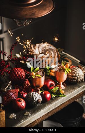 Christmas or Thanksgiving Day festive homemade bundt cake with sparklers and winter ice refreshing citrus cocktails in copper goblets on kitchen counter. Winter holidays festive mood concept Stock Photo