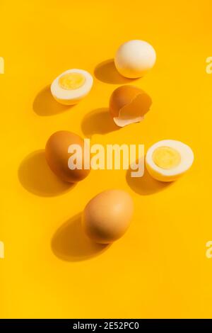 Brown chicken raw and hard boiled fresh eggs on yellow background. Healthy food or Happy Easter concept. Top view, flat lay Stock Photo