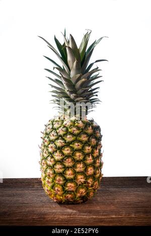 Big tropical pineapple with its leaves on a barn wood board on white background Stock Photo