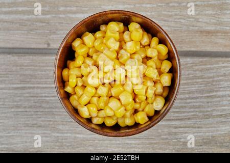 A bowl of boiled sweet corn on a wooden table Stock Photo