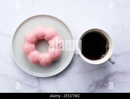 Hot coffee with pink donuts on a marble background. View from above Stock Photo