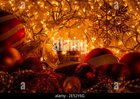Decorative ball with a deer inside, close-up with blurred Christmas lights. Toys for New Years celebration. Festive party decoration. Stock Photo
