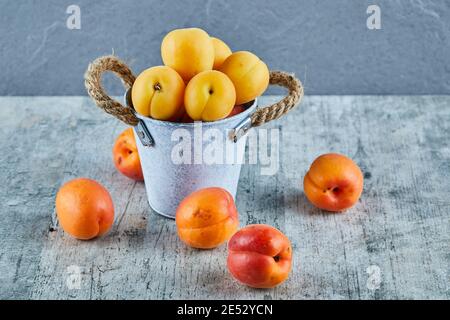 Delicious ripe apricots in iron bucket with nectarines on marble background Stock Photo