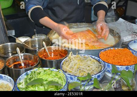 Street food market in Jiaxing, Zhejiang, China. Pancake or spring rolls with vegetables. Jan 2020 Stock Photo