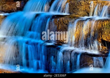 A beautiful lighted waterfall flowing over rock steps on the Athabasca river in Jasper National Park in Alberta Canada. Stock Photo