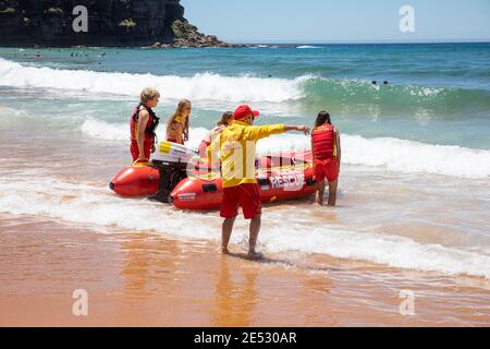 Volunteer surf rescue lifesavers launch inflatable red zodiac surf rescue boat at Bilgola Beach in Sydney,NSW,Australia Stock Photo