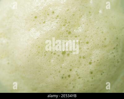 Green foam texture extreme close up as background. Perfect green matcha tea latte foam with bubbles macro shoot. Copy space for text. Stock Photo