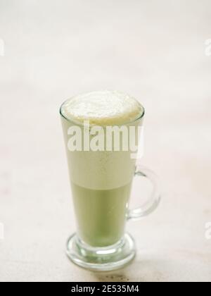 Matcha green tea latte in glass. Matcha latte on light background. Copy space. Vertical Vertical. Stock Photo