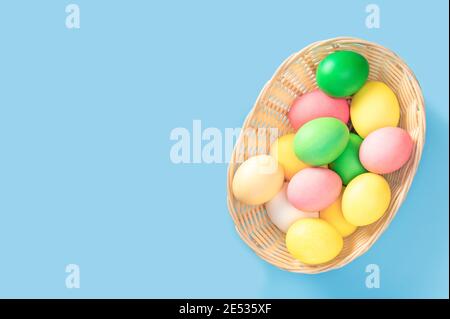 Easter Eggs In Basket. Basket with easter eggs. Basket Of Colorful Easter Eggs on blue background. Easter concept. Top view, copy space Stock Photo