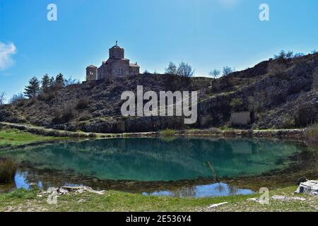 Medieval castle view at the beautiful green lake/ church at the top of the cliff surrounded whit Mountain Stock Photo
