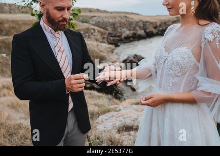 A man proposes to a woman to get engaged by putting a ring on her finger. Stock Photo