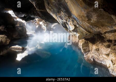 Icelandic natural cave flooded with steaming blue geothermal water Stock Photo