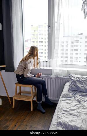 woman sitting on chair and looking at window outside expecting someone Stock Photo