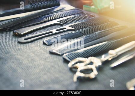 Combs, brushes and scissors on the table in the barbershop. Selective soft focus, lens glare Stock Photo