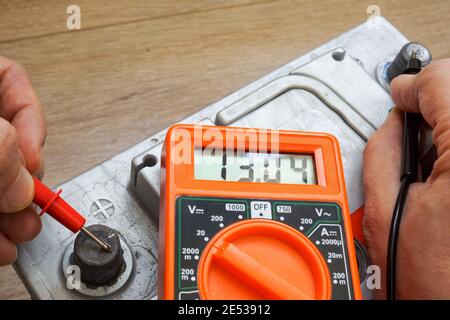 Hands with a voltmeter check the charge level of the car battery. Stock Photo